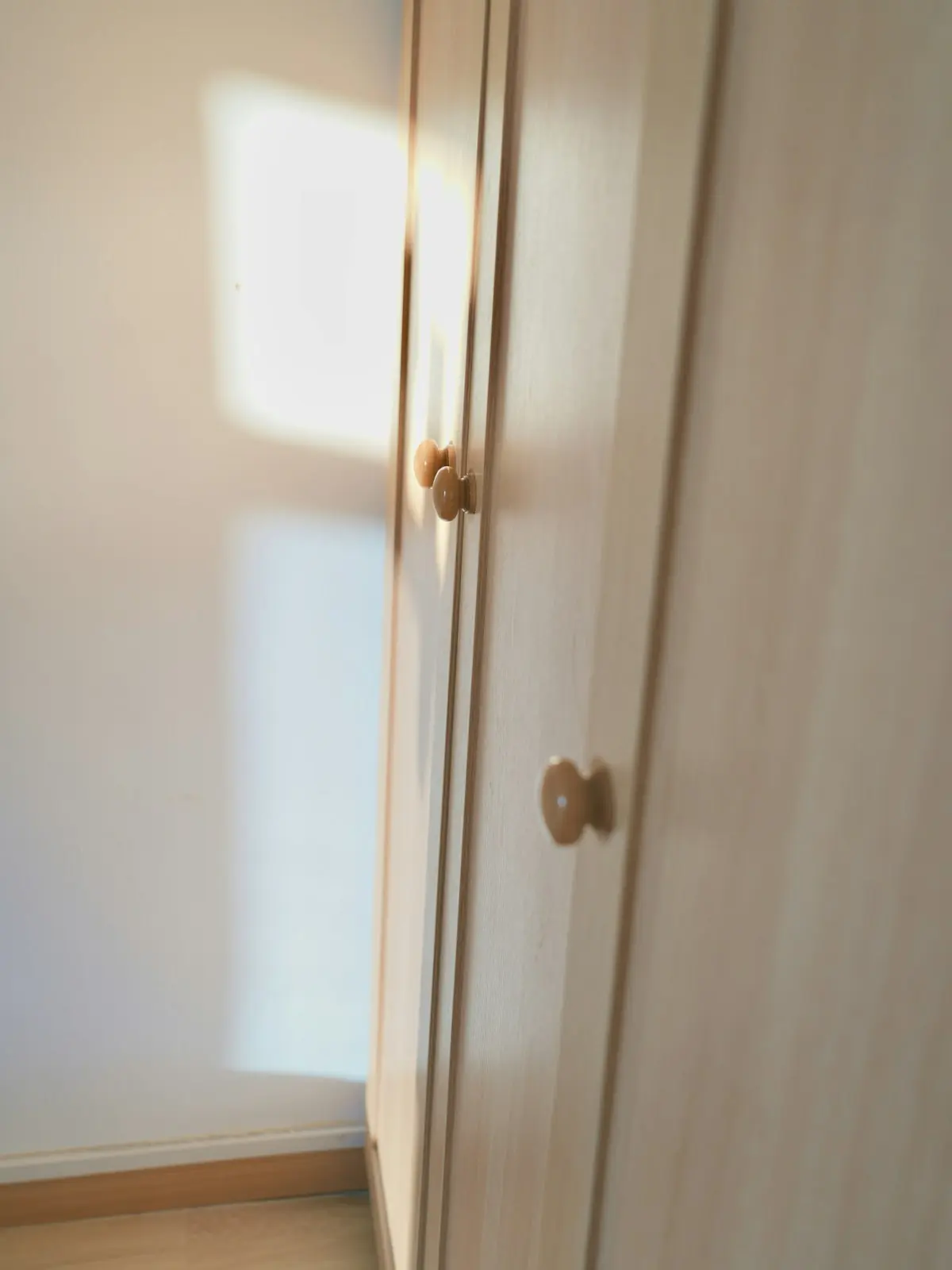 Schrankfront aus Holz mit Messinggriff im Sonnenlicht